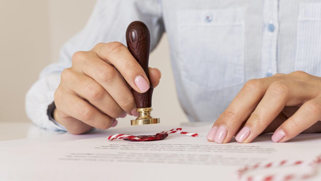 person-using-wax-seal-blurred-certificate